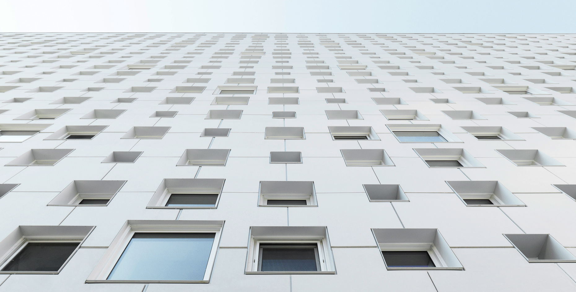 The different sized windows and natural white color of the panels lend the outer wall an extravagant yet simple appearance.
